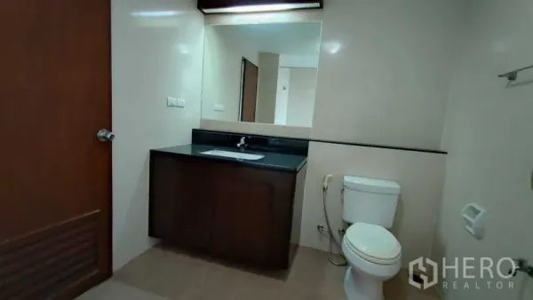 คอนโด ให้เช่าในKhlong Toei, Bangkok - ห้องน้ำกว้าง กระจกบานใหญ่ เคาน์เตอร์อ่างล้างหน้าโทนเข้ม และโถสุขภัณฑ์