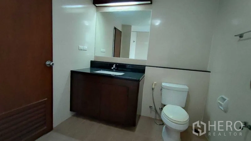 คอนโด ให้เช่าในKhlong Toei, Bangkok - ห้องน้ำกว้าง กระจกบานใหญ่ เคาน์เตอร์อ่างล้างหน้าโทนเข้ม และโถสุขภัณฑ์