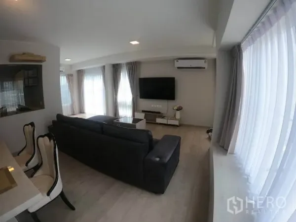 Detached House for rent in Prawet, Bangkok - Living area with multiple curtained windows, air-conditioning and TV feature wall.