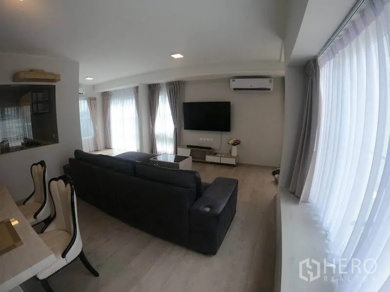 Detached House for rent in Prawet, Bangkok - Living area with multiple curtained windows, air-conditioning and TV feature wall.
