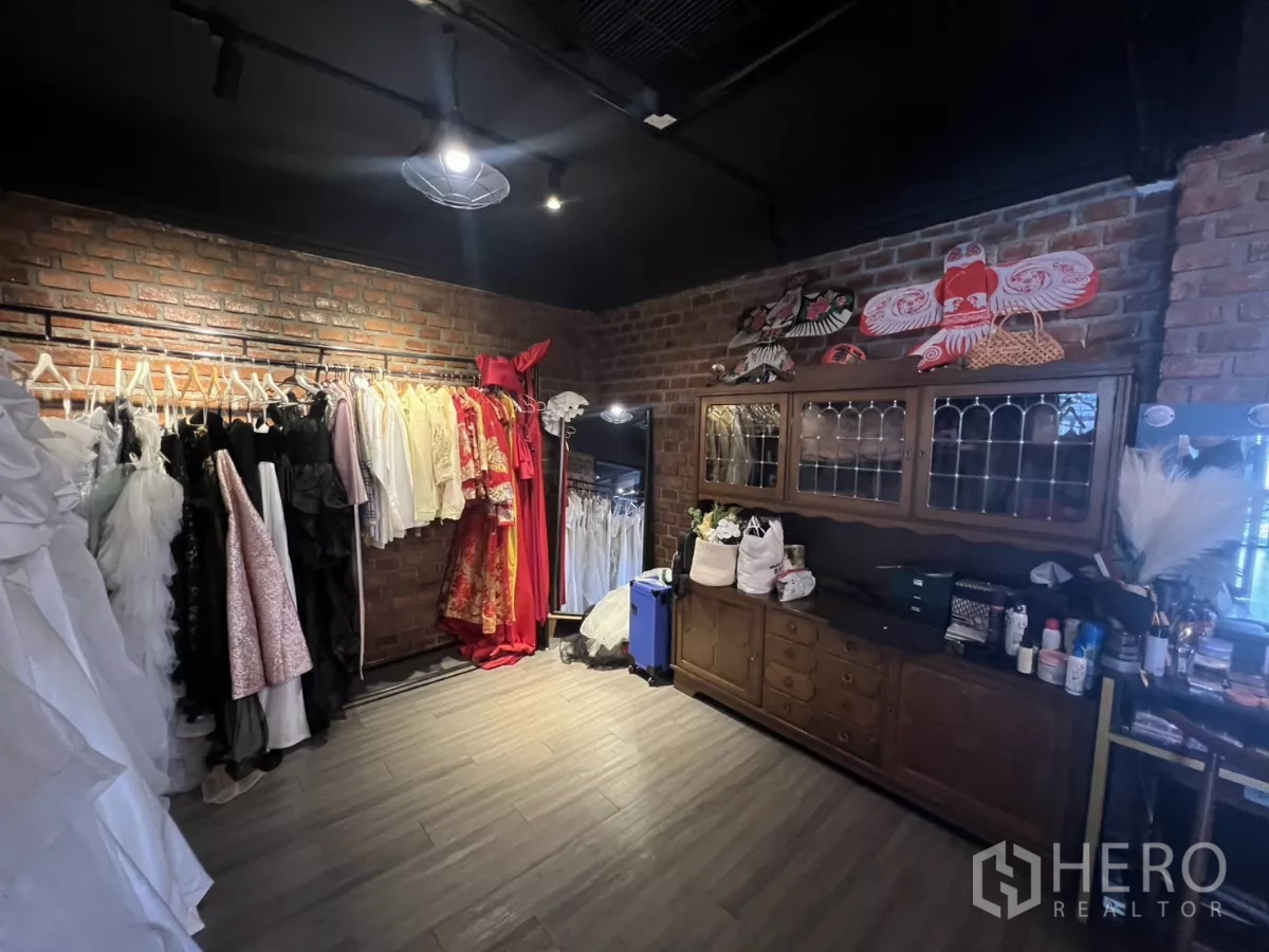 零售空间 出租在Watthana, Bangkok - 更衣室带砖墙、服装挂架与复古柜。