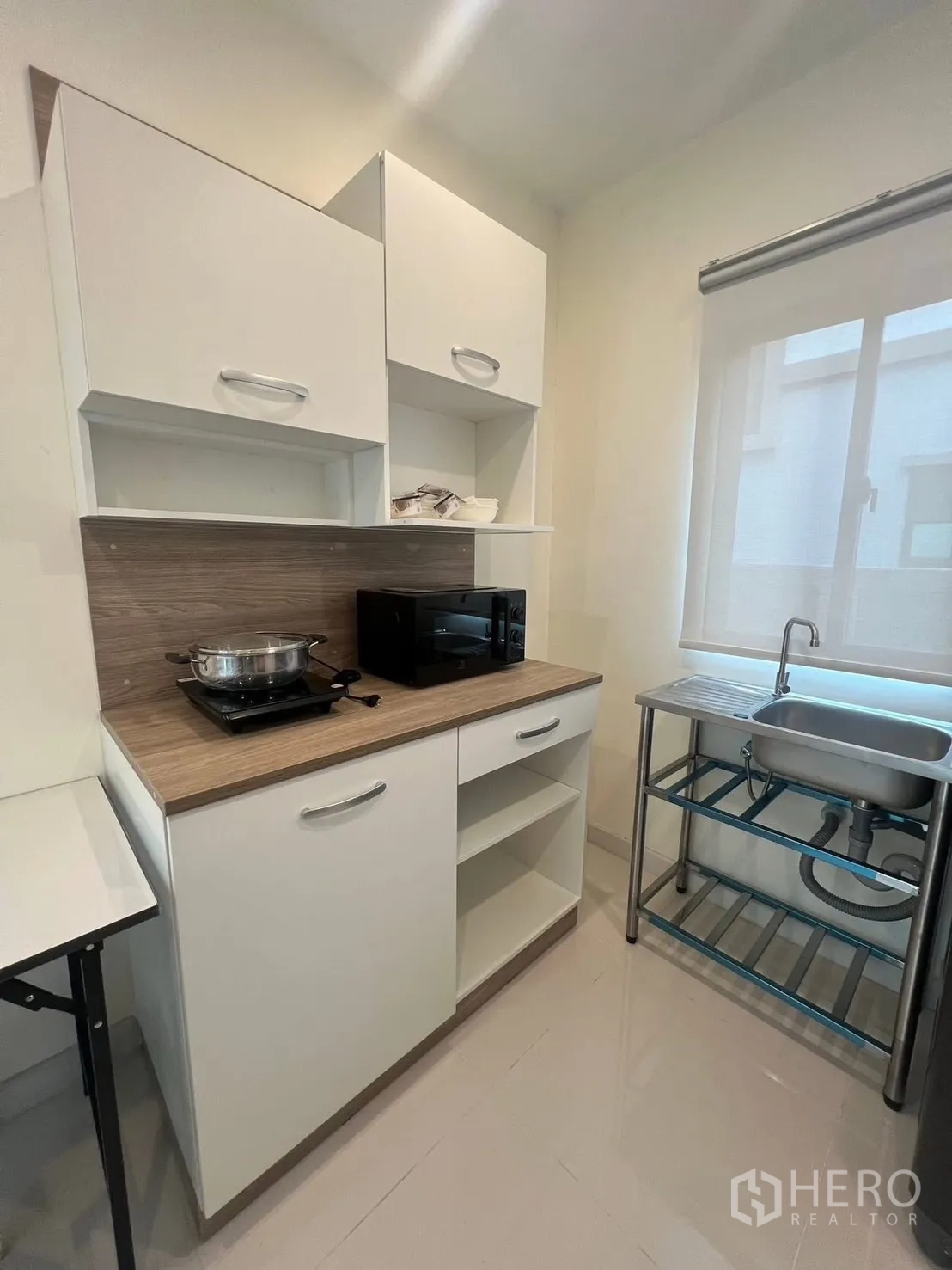 Detached House for rent in Bang Phli, Samut Prakan - Compact pantry kitchen with white cabinets, countertop, microwave and stainless sink by a window.