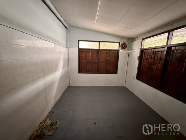 零售空间 出租在Khlong Toei, Bangkok - 空置瓷砖房，木窗与墙上排风扇，适合储物或工作区