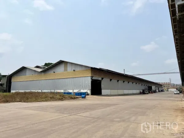 Warehouse for rent in Phra Samut Chedi, Samut Prakan - Corner view of long-span warehouse with open loading bays and side canopy.
