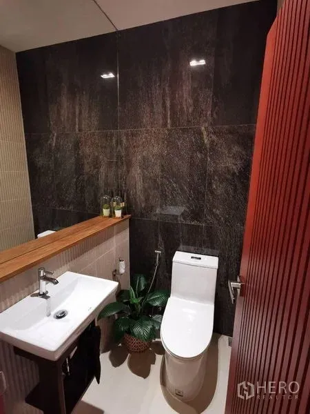 ทาวน์เฮาส์ ให้เช่าหรือขายในYan Nawa, Bangkok - ห้องน้ำสไตล์โมเดิร์น ผนังหินโทนเข้ม อ่างล้างหน้า สุขภัณฑ์ และชั้นไม้พร้อมต้นไม้กระถาง