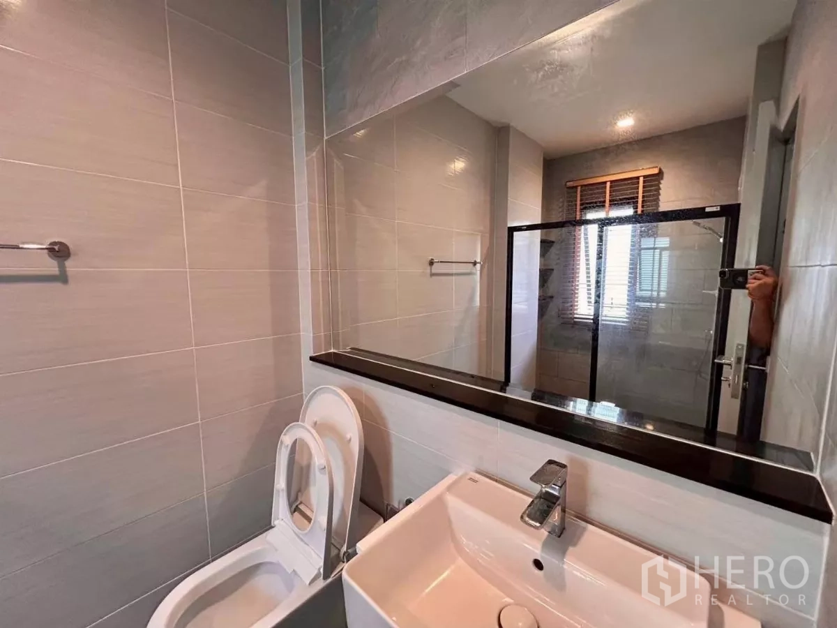 Detached House for rent in Bang Phli, Samut Prakan - Contemporary bathroom with glass shower enclosure, large mirror and white vanity.
