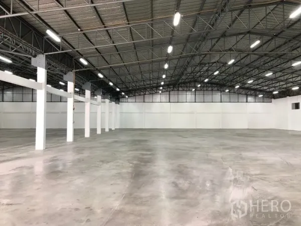 Warehouse for rent in Pak Kret, Nonthaburi - Expansive warehouse interior with high steel truss roof, bright LED lighting and polished concrete floor.