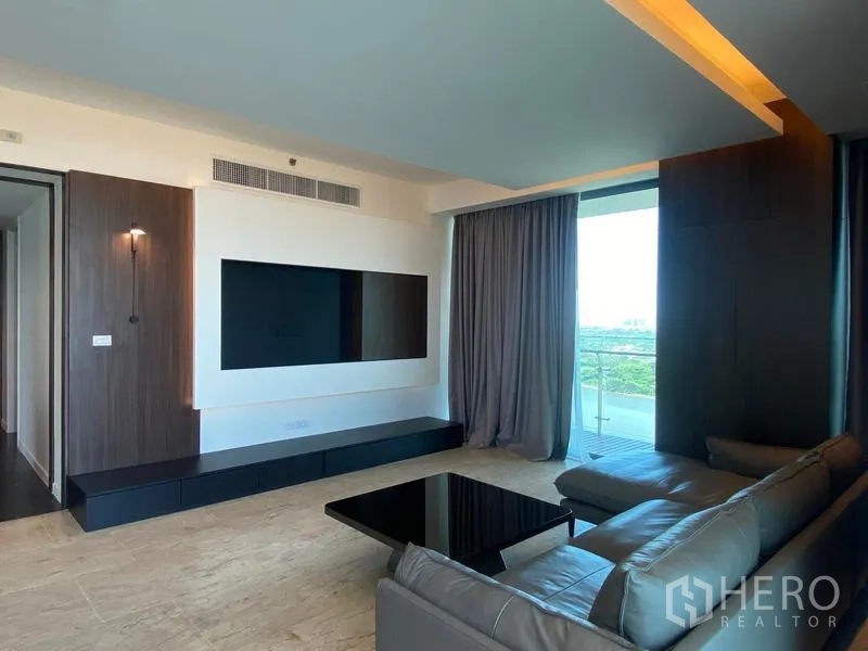 Condominium for rent - Living area with TV feature wall, gray sofa and balcony access.