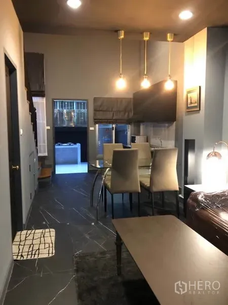 ทาวน์เฮาส์ ให้เช่าในBang Kapi, Bangkok - มุมมองไปยังโต๊ะทานอาหารและครัว พื้นกระเบื้องสีเข้มและไฟแขวนสามดวง