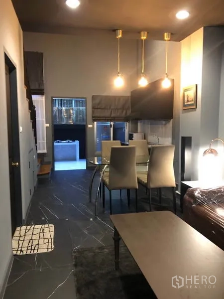 ทาวน์เฮาส์ ให้เช่าในBang Kapi, Bangkok - มุมมองไปยังโต๊ะทานอาหารและครัว พื้นกระเบื้องสีเข้มและไฟแขวนสามดวง