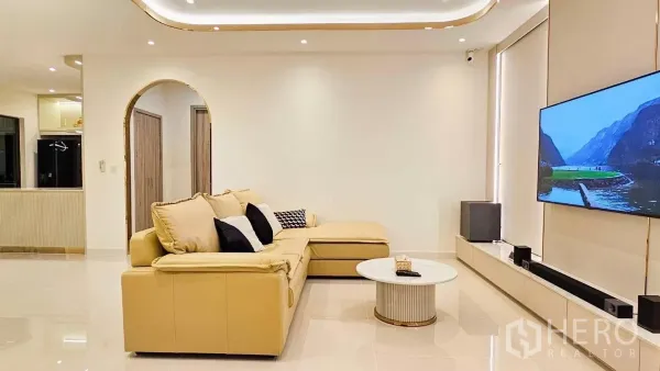 บ้าน ให้เช่าหรือขายในPrawet, Bangkok - ห้องนั่งเล่นสว่าง โซฟาแอลหนัง ทีวีติดผนัง ไฟดาวน์ไลท์ และพื้นกระเบื้องเงา