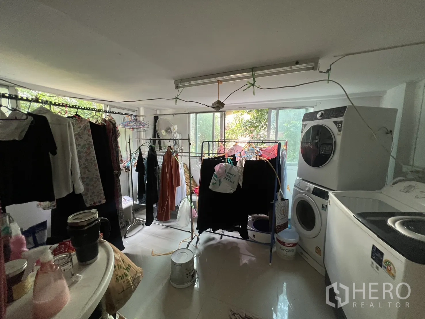พื้นที่ขายปลีก ให้เช่า - ห้องซักล้างและตากผ้า มีราวหลายชุดและเครื่องซักผ้า ใกล้หน้าต่างบานใหญ่
