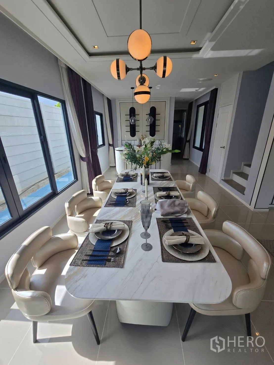 Semi-detached House for rent in Bang Phli, Samut Prakan - Dining room with long marble table set for eight under modern pendant lights.