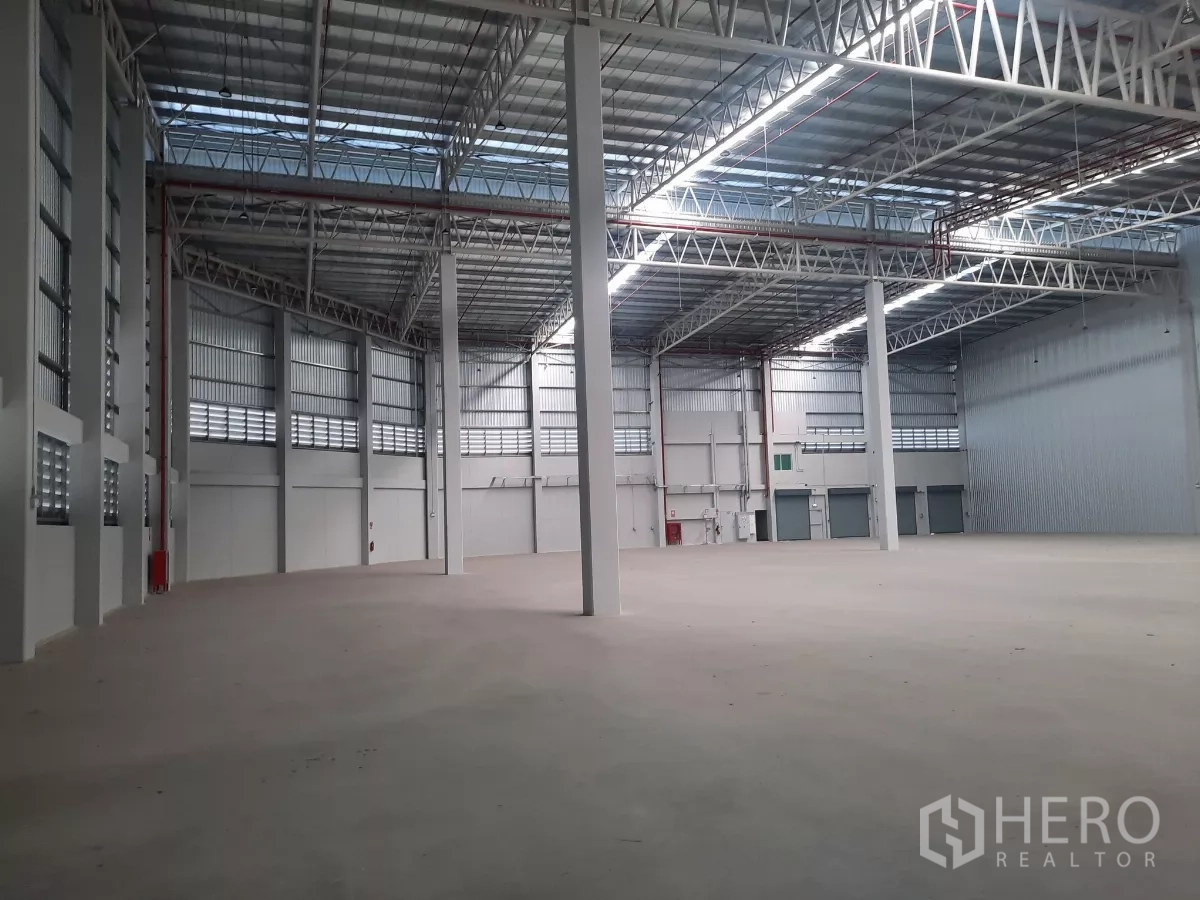 工厂 出租在Bang Lamung, Chon Buri - 高净空仓库内部，钢桁架屋顶、混凝土地面与高立柱。