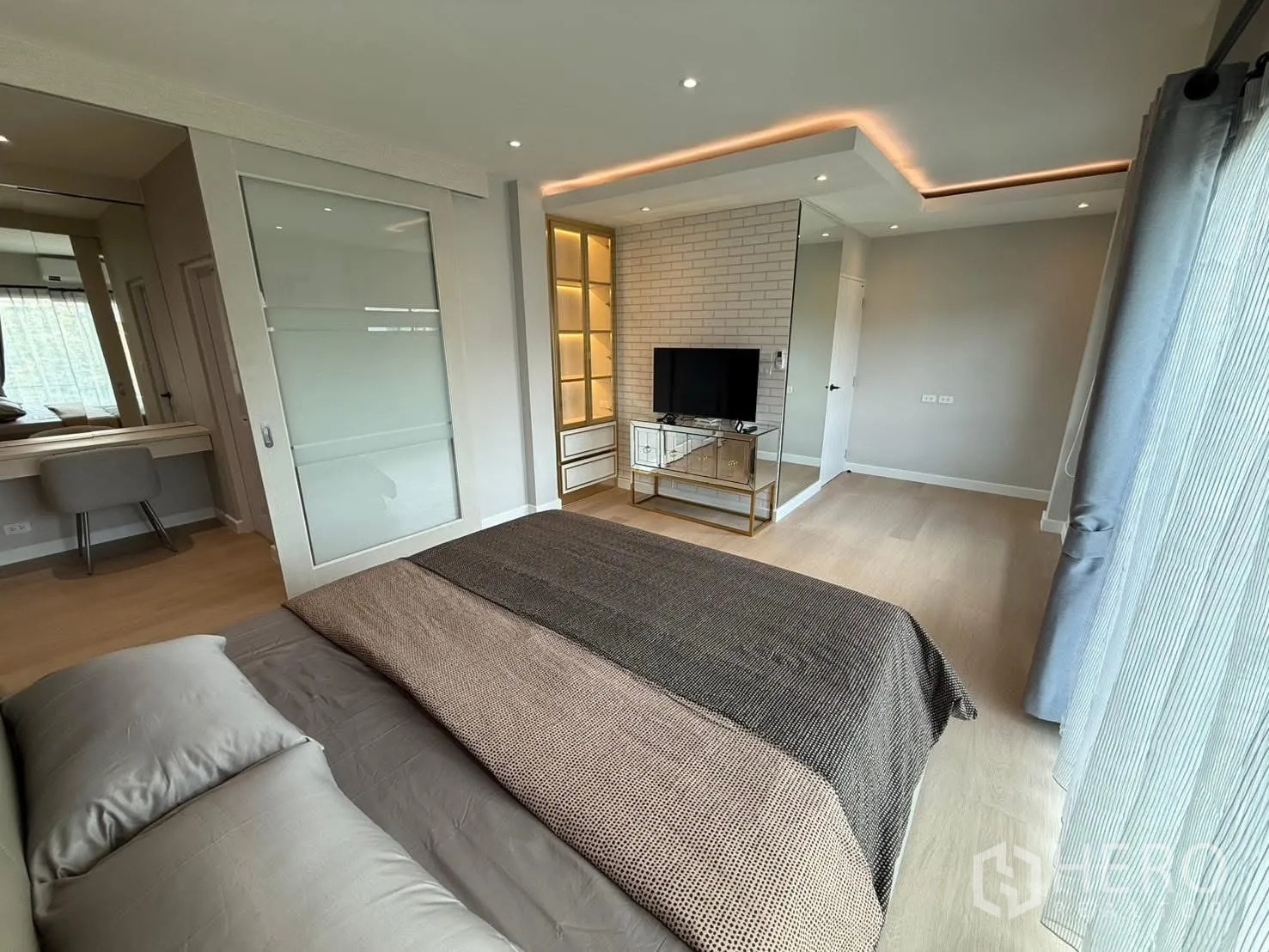 Detached House for rent in Prawet, Bangkok - Master bedroom showing vanity, sliding glass wardrobe door, recessed lighting and upholstered bed.