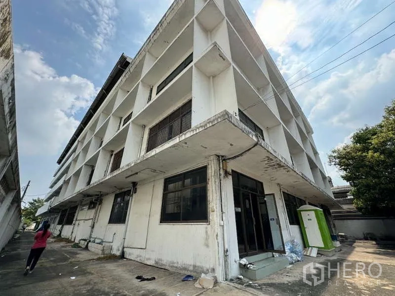 Home Office for sale in Bang Na, Bangkok - Corner angle of multi-storey building facade with wide windows and side walkway.