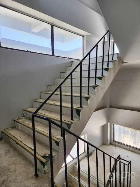 工厂 出租或出售在Khlong Toei, Bangkok - 混凝土楼梯配黑色金属扶手，楼梯间大窗采光。