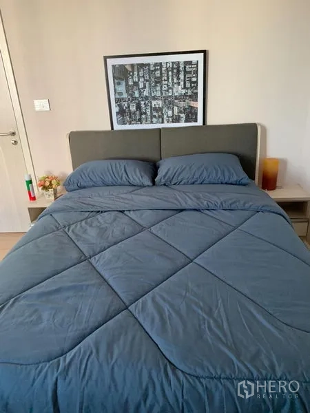 ทาวน์เฮาส์ ให้เช่าในSuan Luang, Bangkok - ห้องนอนรับรอง เตียงหัวบุผ้าสีเทา ชุดเครื่องนอนสีน้ำเงิน และโต๊ะหัวเตียง