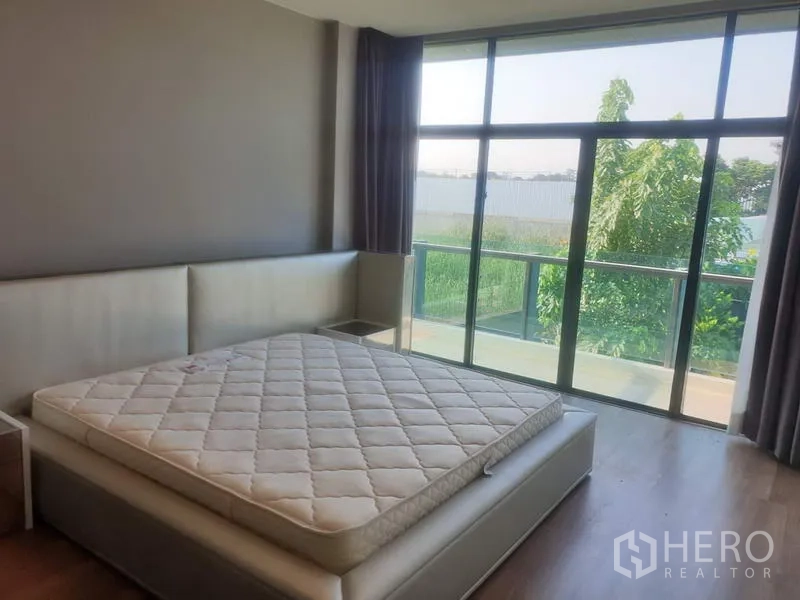 Detached House for sale in Bang Kapi, Bangkok - Master bedroom with large windows, balcony access and green garden view.