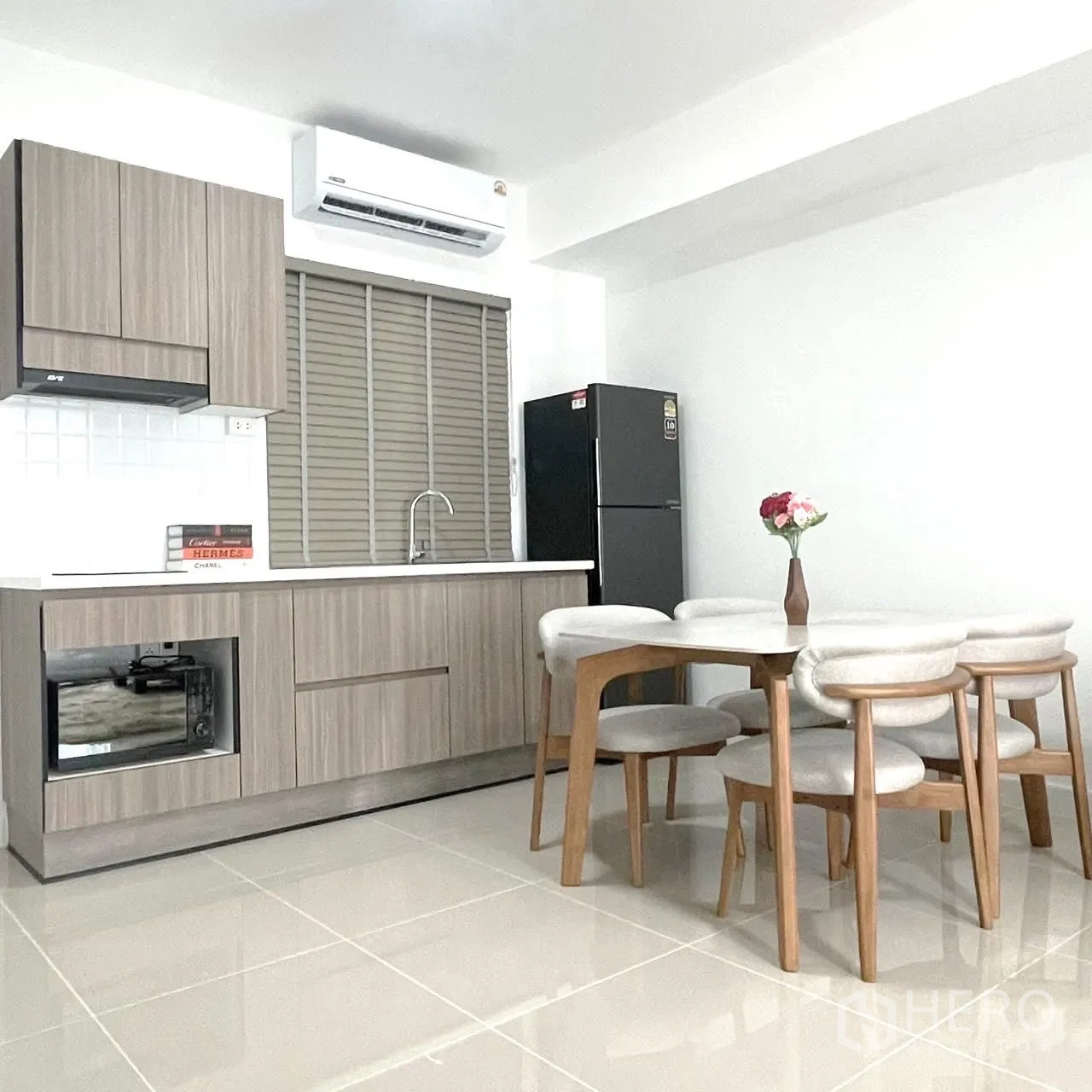 Townhouse for rent in Bang Phli, Samut Prakan - Compact modern kitchen with wood cabinets, sink, fridge, and a dining set.