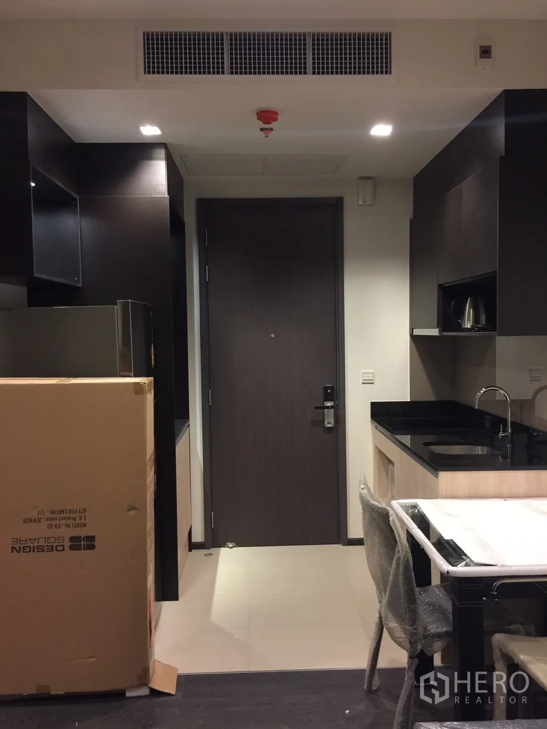 公寓 出租在Watthana, Bangkok - 开放式厨房，黑色台面与嵌入式橱柜，设用餐角。