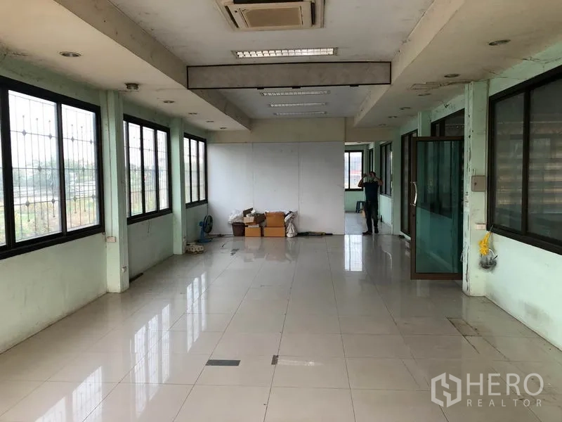 货栈 出租在Nonthaburi - 二层办公室，落地窗采光，瓷砖地面与玻璃门，吊顶空调。