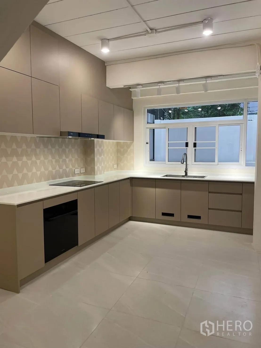 ทาวน์เฮาส์ for rent in Huai Khwang, Bangkok - ครัวรูปตัว U ทันสมัย พร้อมตู้เก็บของ เตาและเตาอบบิลท์อิน และหน้าต่าง.
