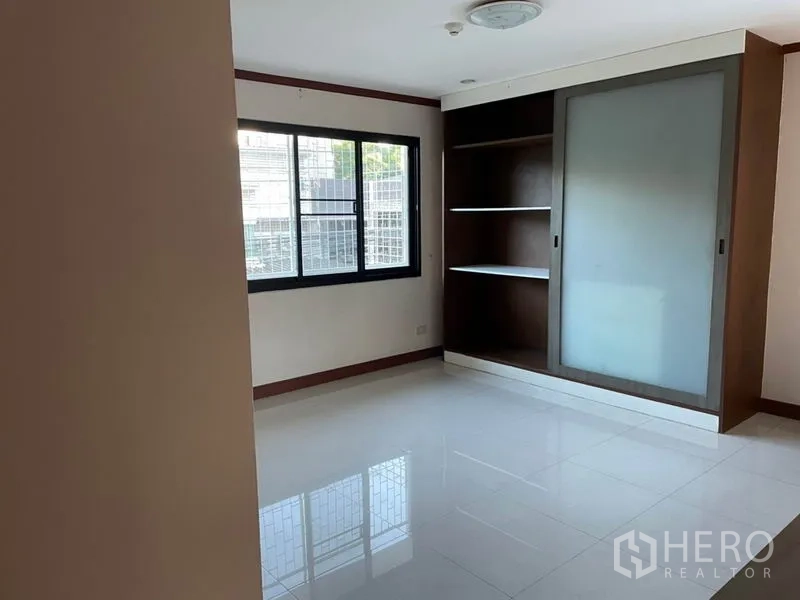 Office Space for rent in Khlong Toei, Bangkok - Bright empty office room with large window, built-in shelving and frosted sliding-door cabinet