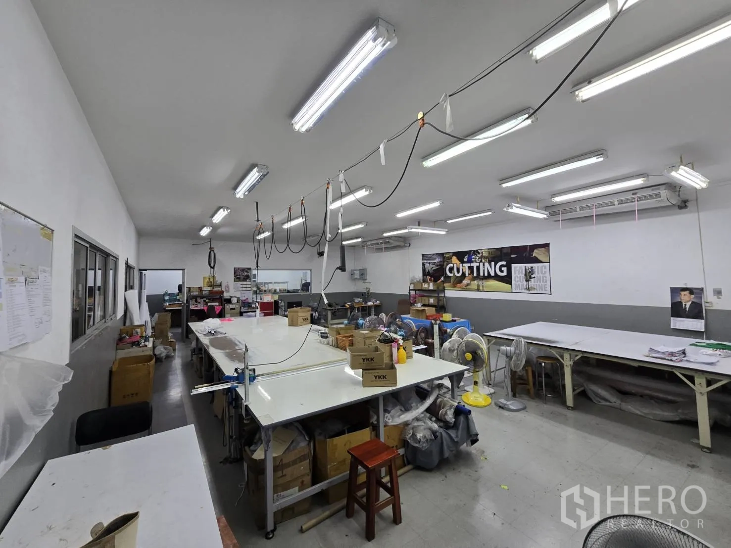 Factory for rent in Sam Phran, Nakhon Pathom - Cutting room featuring long worktables, overhead power rails, and storage.