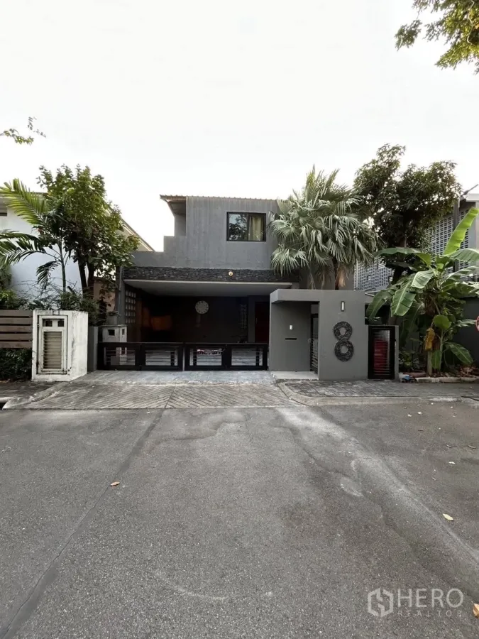 Detached House for rent or sale in Wang Thonglang, Bangkok - Modern two-storey detached house facade with gated carport and tropical trees in Wang Thonglang, Bangkok.