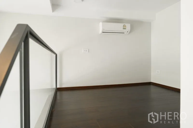 Condominium for sale in Watthana, Bangkok - Open mezzanine bedroom space with glass balustrade and an air-conditioning unit.