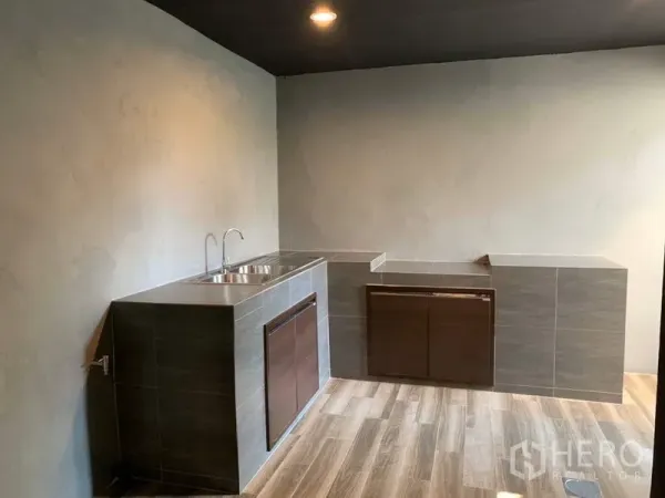 联排别墅 出租在Bang Kapi, Bangkok - 极简泰式厨房，瓷砖台面、双槽水槽与木纹地面。