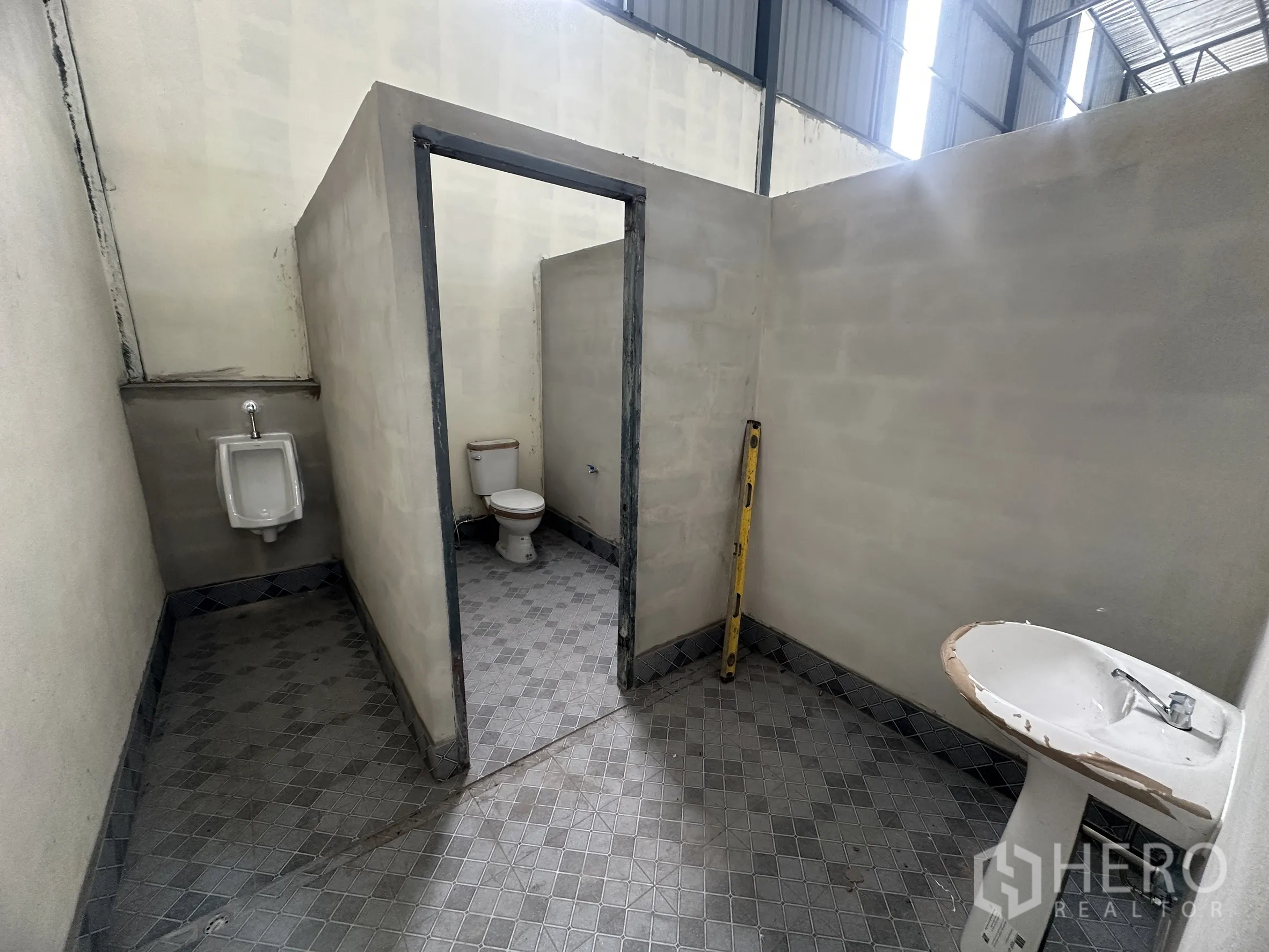 Warehouse for rent in Lam Luk Ka, Pathum Thani - On-site restroom block with a toilet, urinal, and sink inside the warehouse.