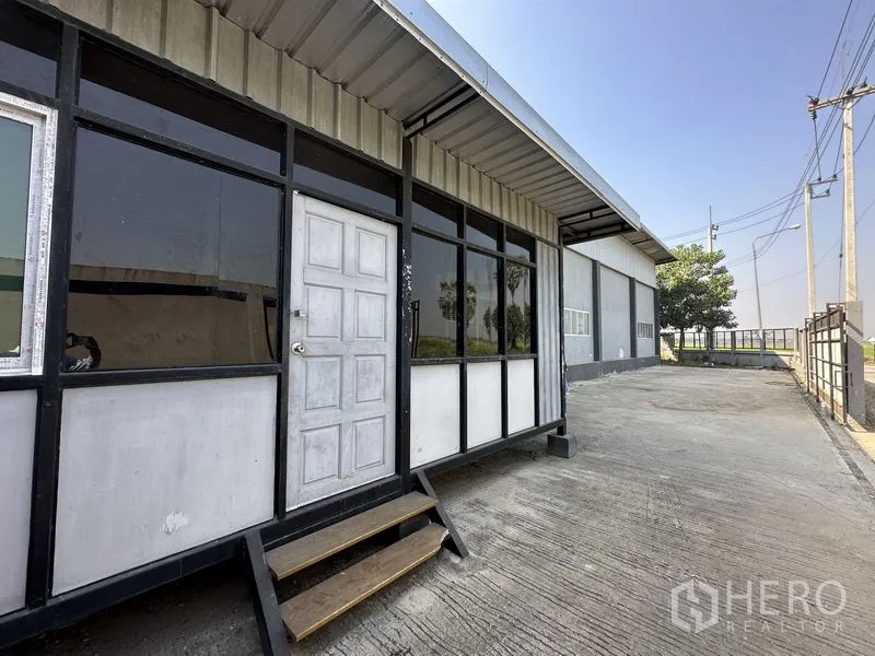 工厂 出租在Lam Luk Ka, Pathum Thani - 前部模块化办公室立面，玻璃门窗与台阶，旁有宽敞车道。