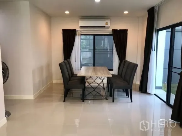 Detached House for rent in Bang Kapi, Bangkok - Dining area with table and upholstered chairs next to large windows and air conditioner.