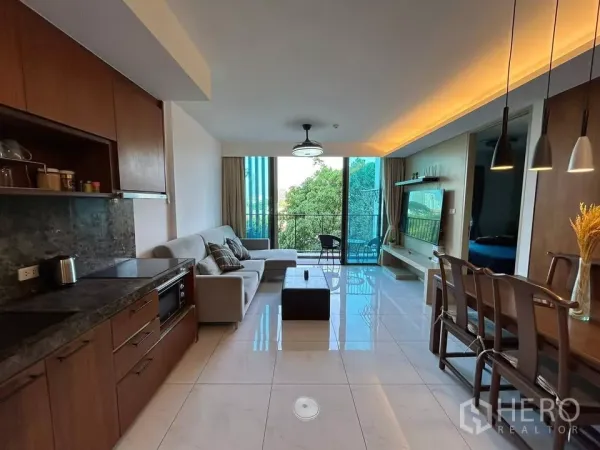 Condominium for rent in Watthana, Bangkok - Open-plan living area with kitchen, sofa, dining set and a balcony looking over greenery.