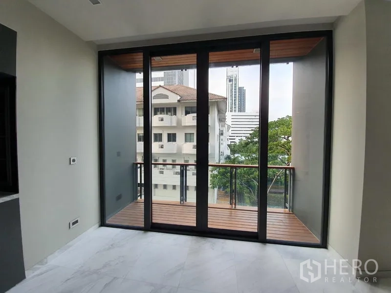 Condominium for rent in Watthana, Bangkok - Private balcony with wood decking and a city view through full-height sliding doors.