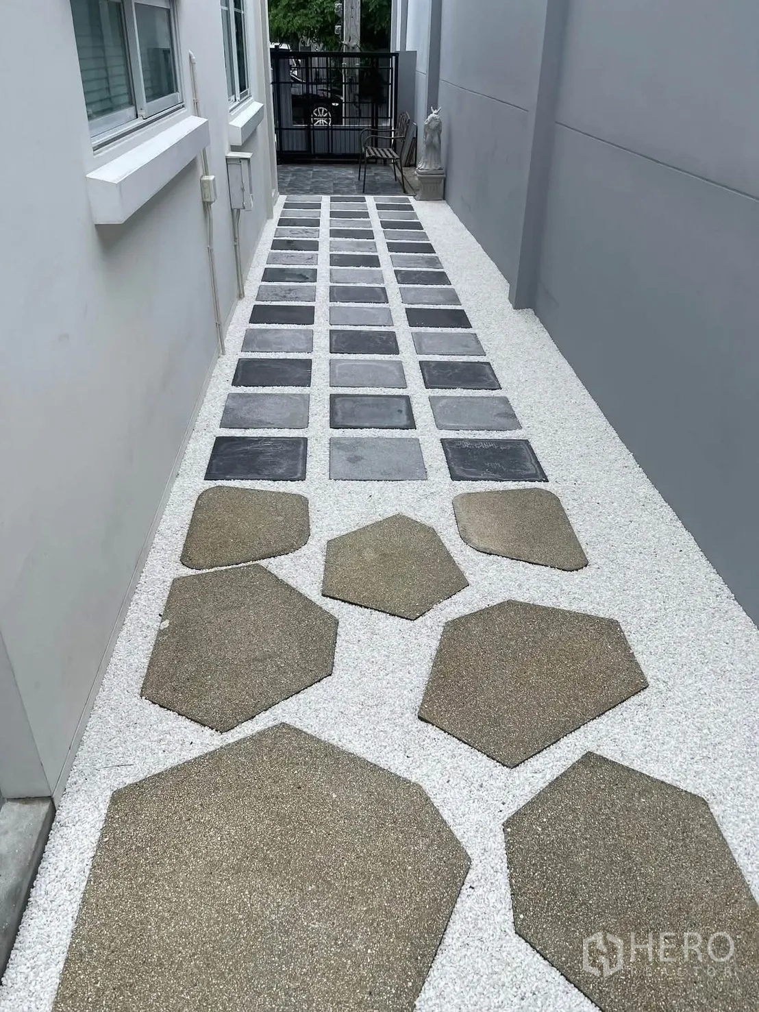 Townhouse for rent in Bang Phli, Samut Prakan - Side yard with geometric stepping stones on white gravel leading to gate.