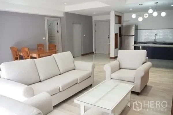 公寓 出租在Pathum Wan, Bangkok - 明亮的客厅，白色沙发与茶几，连通开放式厨房。