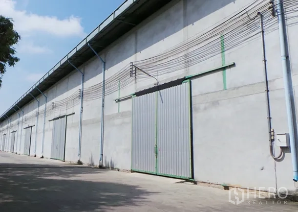 货栈 出租在Prawet, Bangkok - 曼谷帕拉威区混凝土仓库外立面，金属推拉门与车道