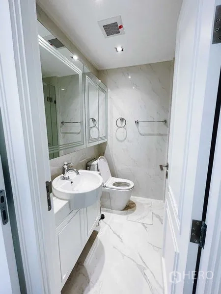 Condominium for rent or sale in Bang Kho Laem, Bangkok - Modern bathroom with white marble-effect walls, vanity, and toilet.