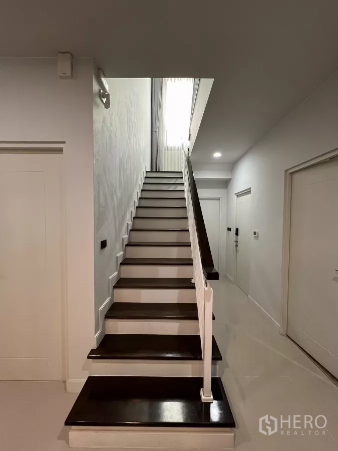 Detached House for rent or sale in Bang Kapi, Bangkok - Staircase with dark wood treads leading to upper floor and skylight.