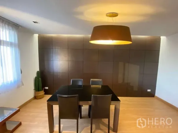 公寓 出租在Khlong Toei, Bangkok - 用餐区，黑色四人餐桌、吊灯与深色饰面墙，旁有纱帘窗。