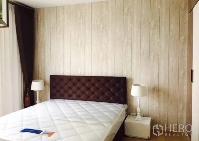 คอนโด ให้เช่าในWatthana, Bangkok - ห้องนอนอบอุ่น หัวเตียงหุ้มบุ ผนังลายไม้ โต๊ะข้างเตียงและโคมไฟ