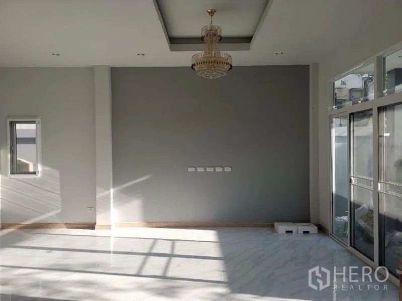 Detached House for rent in Chatuchak, Bangkok - Sunlit living area with chandelier, high ceiling, marble floor, and large glass doors.