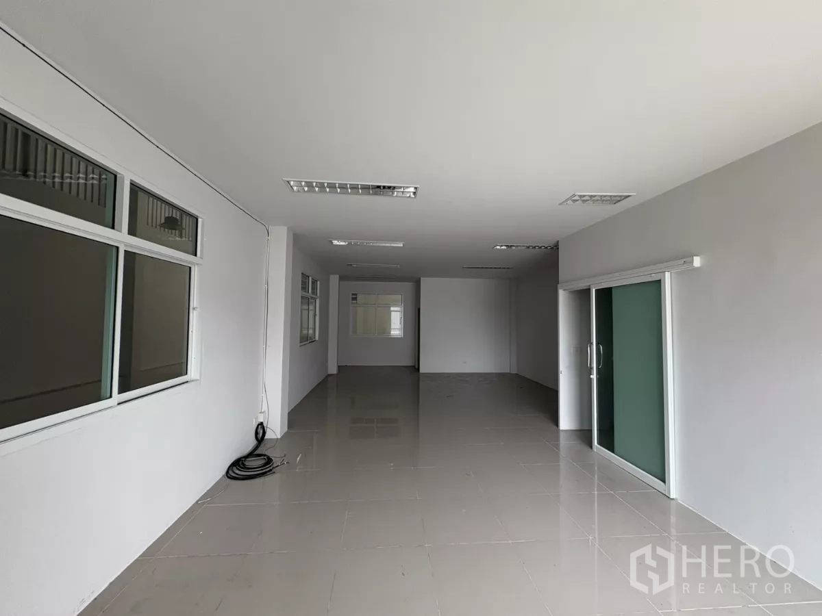 Factory for rent in Phra Samut Chedi, Samut Prakan - Long office corridor with glass partitions and a green sliding door.