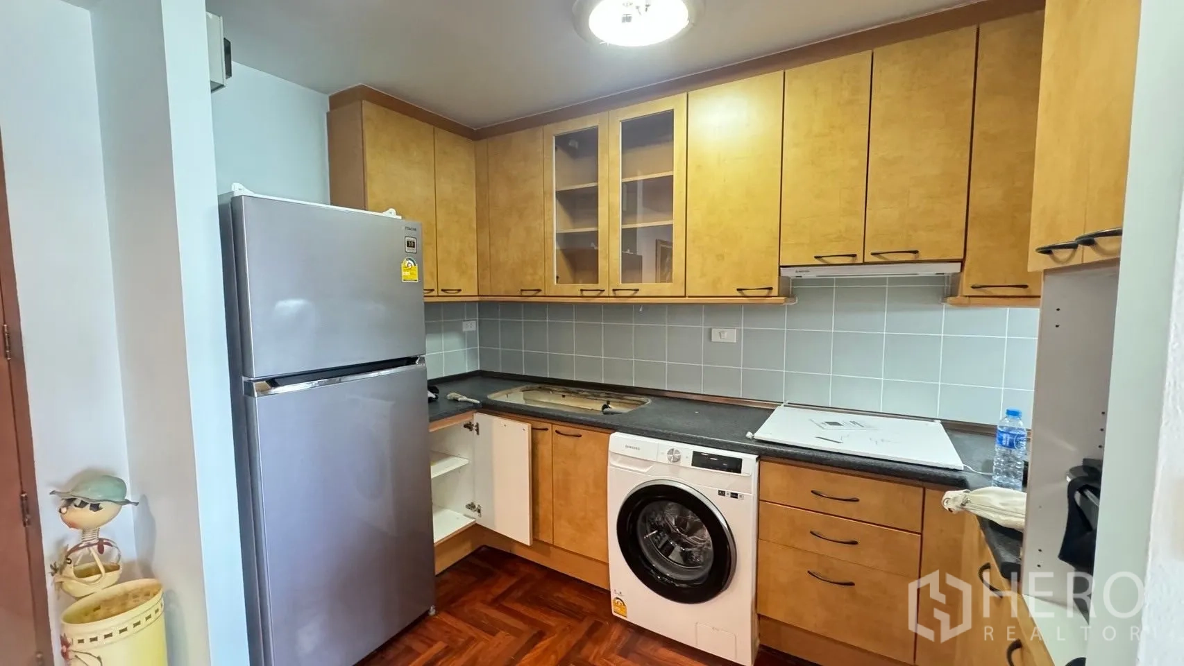 Condominium for rent in Sathon, Bangkok - Built‑in L‑shaped kitchen with ample cabinets, fridge and washing machine.