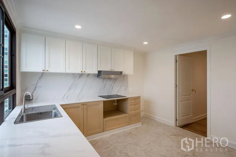 Condominium for sale in Watthana, Bangkok - Separate kitchen with two-tone cabinetry, marble backsplash and cooktop space.