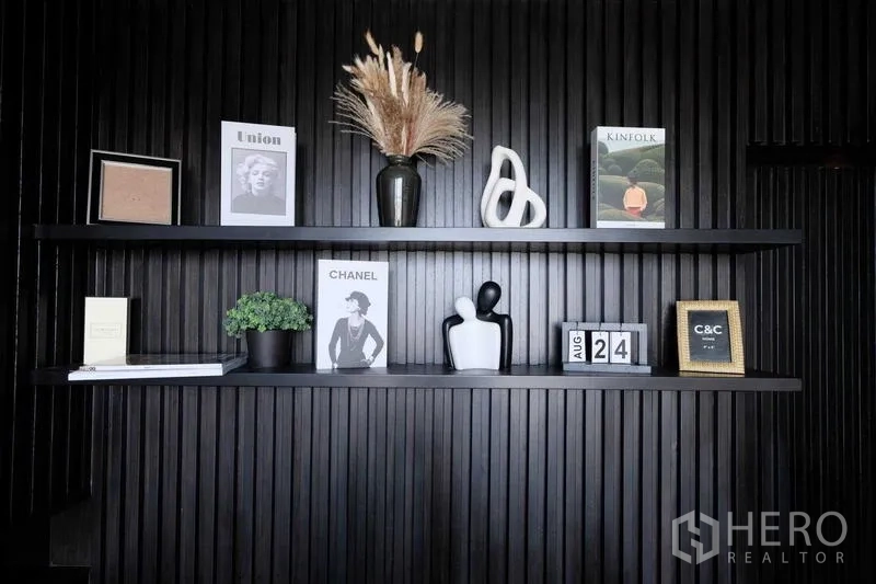 คอนโด ขาย - ชั้นโชว์บนผนังเซาะร่องสีดำ วางหนังสือและของตกแต่ง