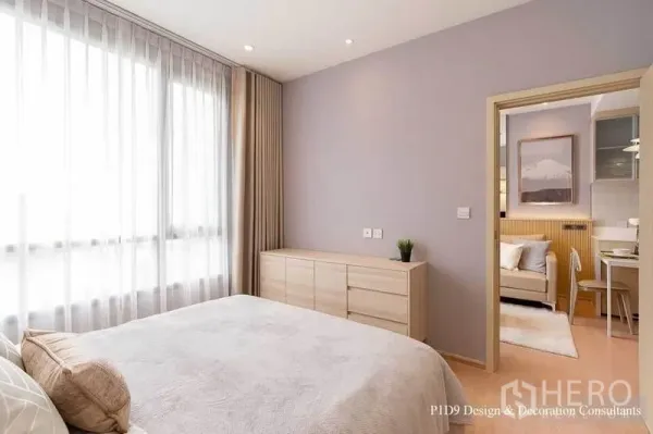 Condominium for rent in Watthana, Bangkok - Bright bedroom with large sheer‑draped window, low dresser and doorway leading to the living area.